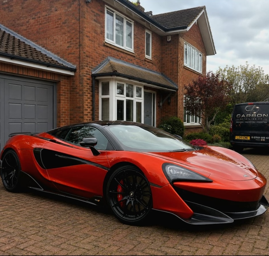 Red McLaren professionally detailed on a driveway with the Carbon Detailing van in the background